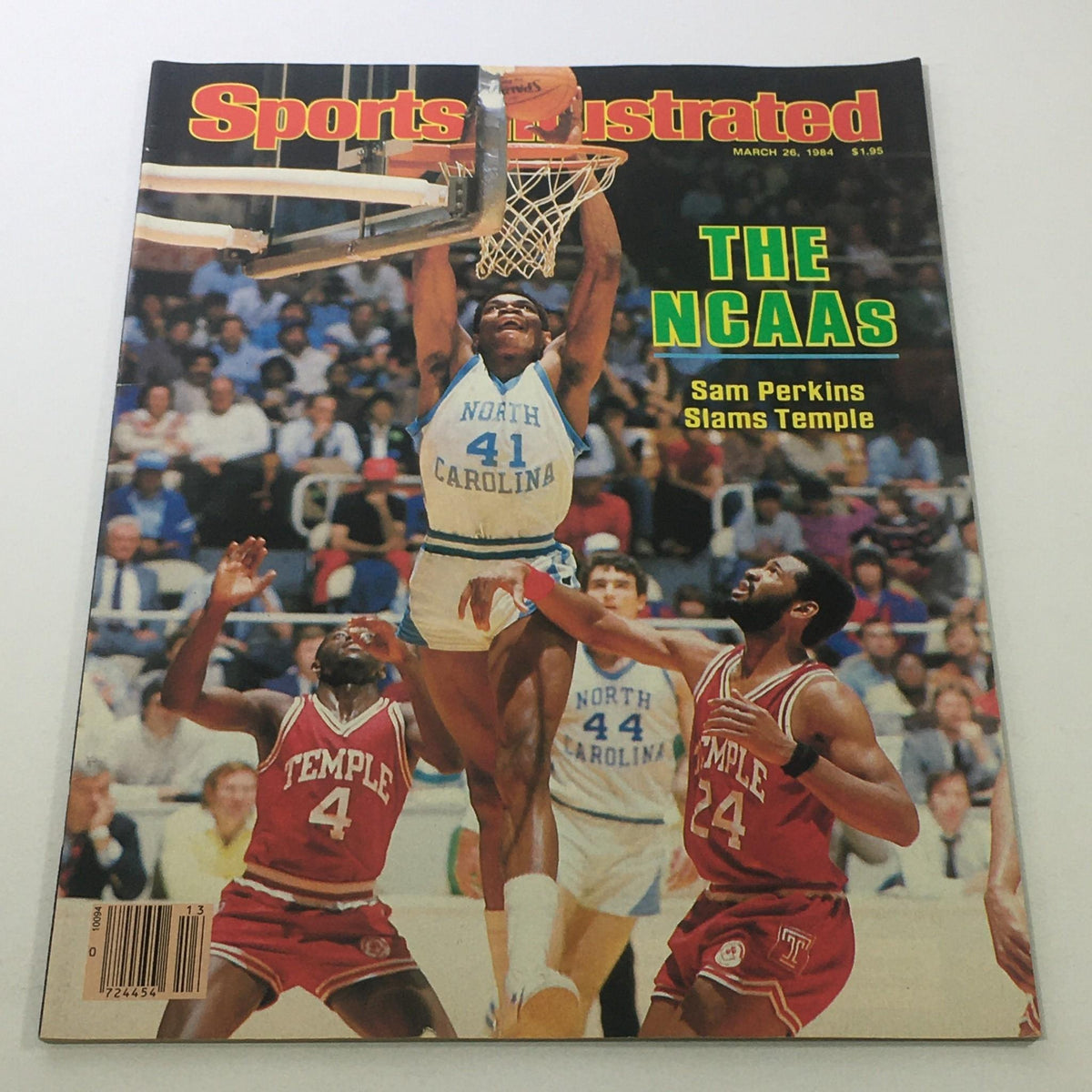 Sports Illustrated cover from March 26, 1984, featuring the NCAA tournament with Sam Perkins slamming over Temple players, showcasing basketball action and historic sports journalism.