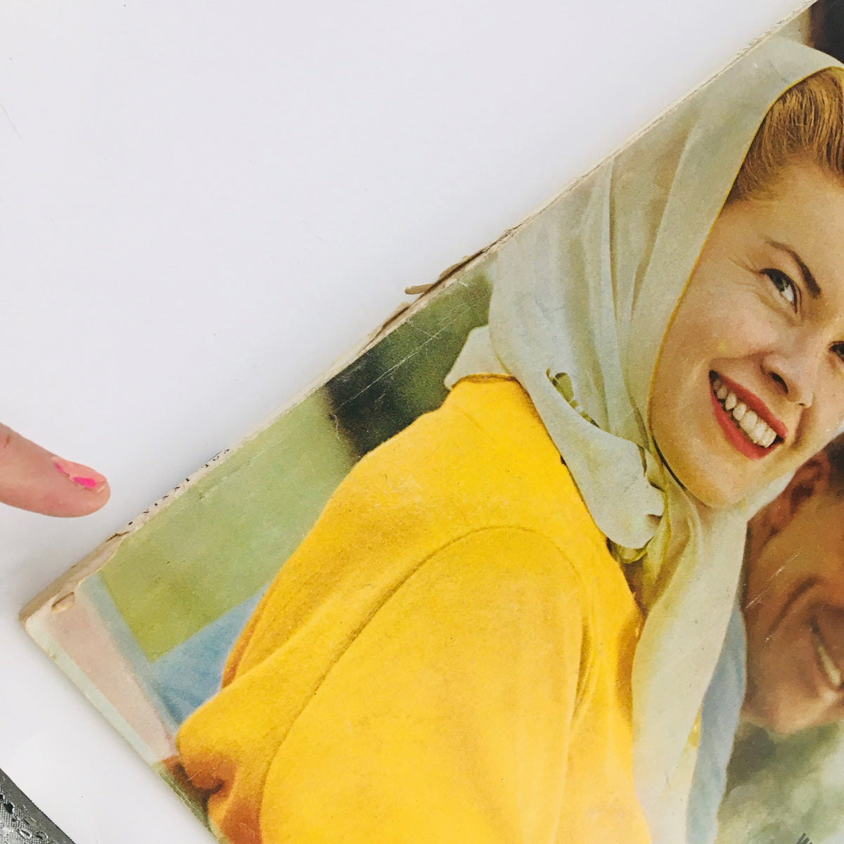 Side view of a vintage Ladies' Home Journal Magazine May 1962 showing wear and tear, with a bright yellow top and a woman smiling, indicative of 1960s culture.