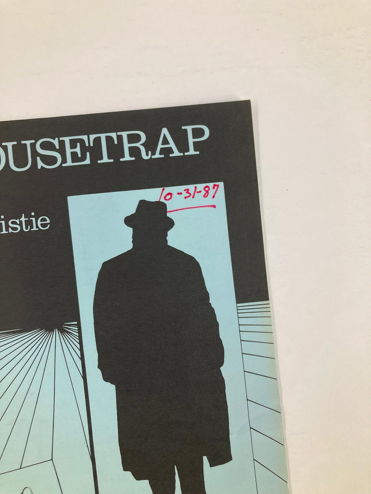 Close-up of the cover of the 1987 Program for The Mousetrap by Agatha Christie showing the silhouette of a figure in a hat and the date "10-31-87" noted in red.