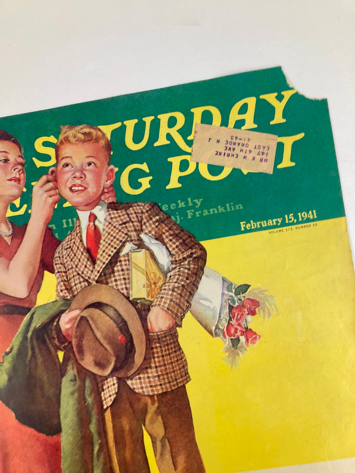 Close-up of The Saturday Evening Post cover from February 15, 1941 titled Muddled Millions, showcasing a boy smiling while holding a hat and a gift, with a woman adjusting his ear.