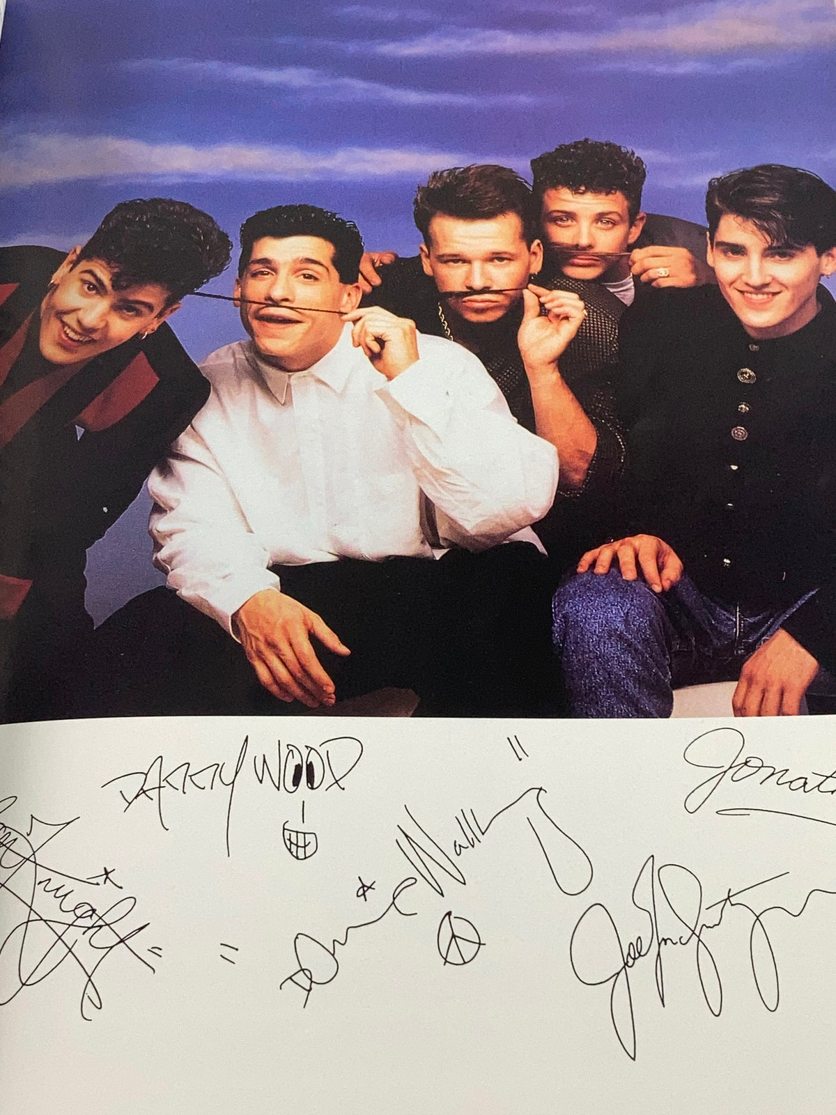 Photograph from 1988 The Official Autobiography Our Story New Kids On The Block displaying band members posing playfully, with signatures underneath.