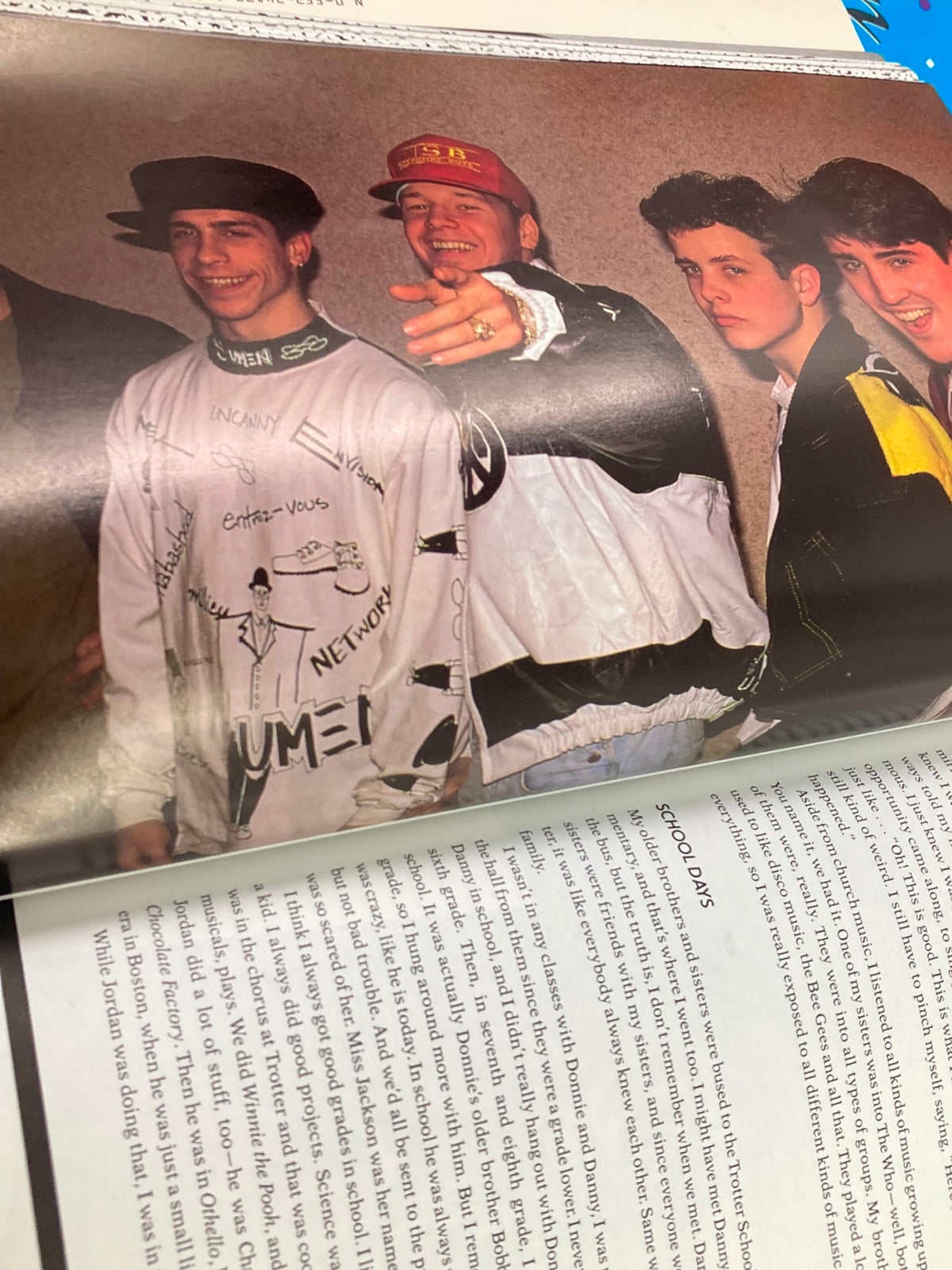 A candid moment featuring members of New Kids On The Block, as seen in '1988 The Official Autobiography Our Story New Kids On The Block'. The image captures the group in stylish 80s outfits, showcasing their youthful energy.