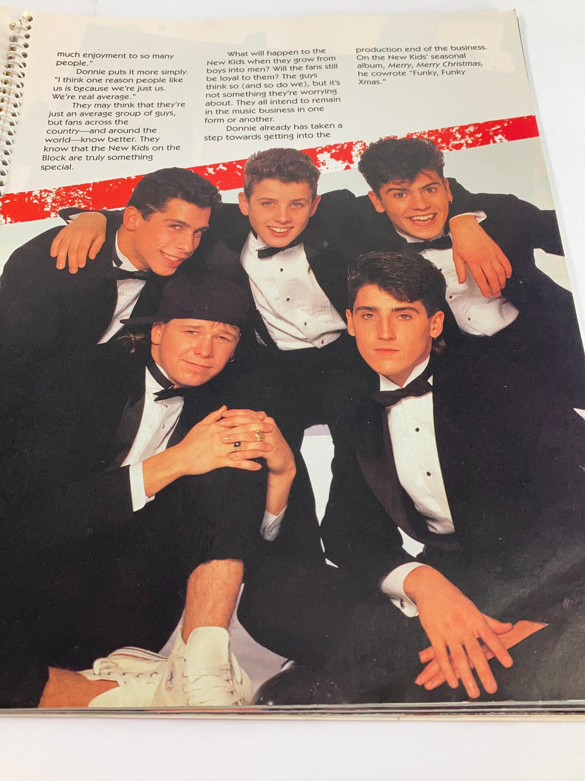 Group photo of the New Kids On The Block from '1990 Publications International, Ltd. Presents New Kids On The Block', featuring the members dressed in formal attire, conveying their pop band aesthetic.
