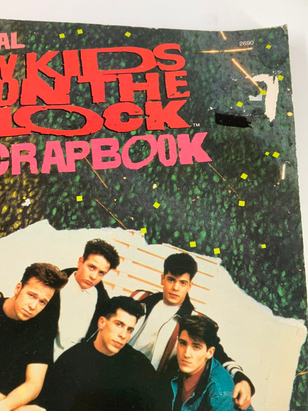 Close-up of the 1989 Official New Kids on The Block Bonus Scrapbook showing band members in a seated pose, detailed with scrapbook elements.
