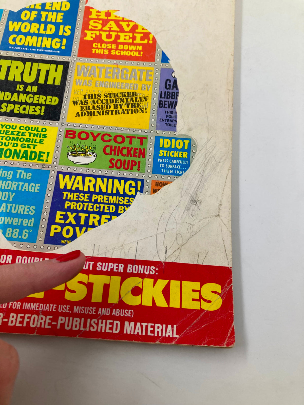 Close-up of the bottom corner of Mad Magazine No. 13, highlighting the 'Mad Sickie-Stickies' feature and humorous advertisements on the cover from 1974.