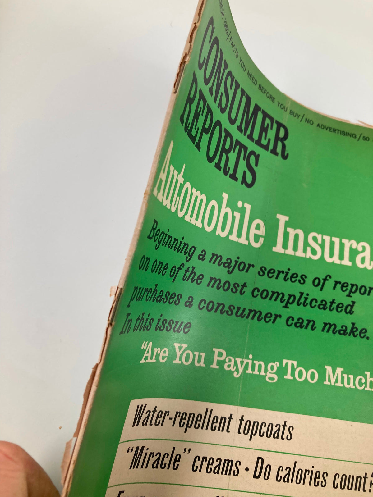 Close-up view of the March 1962 issue of Consumer Reports Magazine cover, focusing on Automobile Insurance and the question 'Are You Paying Too Much?'. This vintage magazine discusses consumer rights and automotive topics.