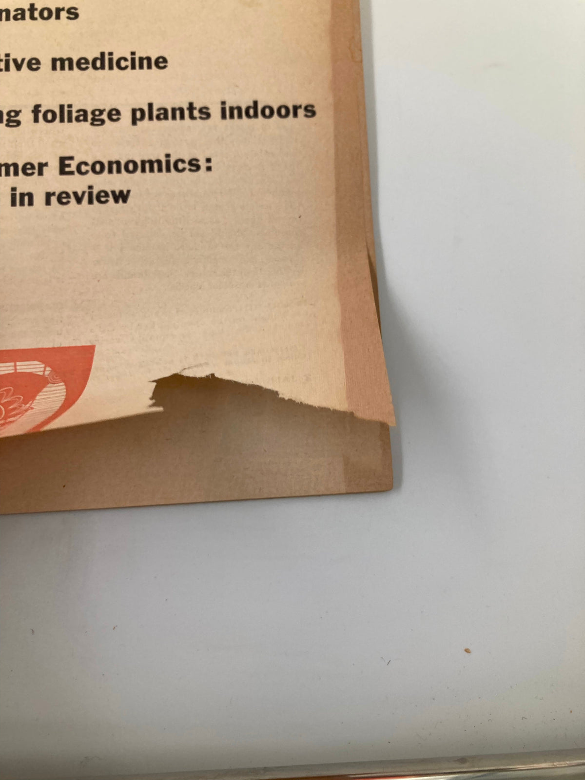 A detailed view of the edge of the vintage Consumer Reports magazine from January 1956, showing wear and tear, including a torn section.