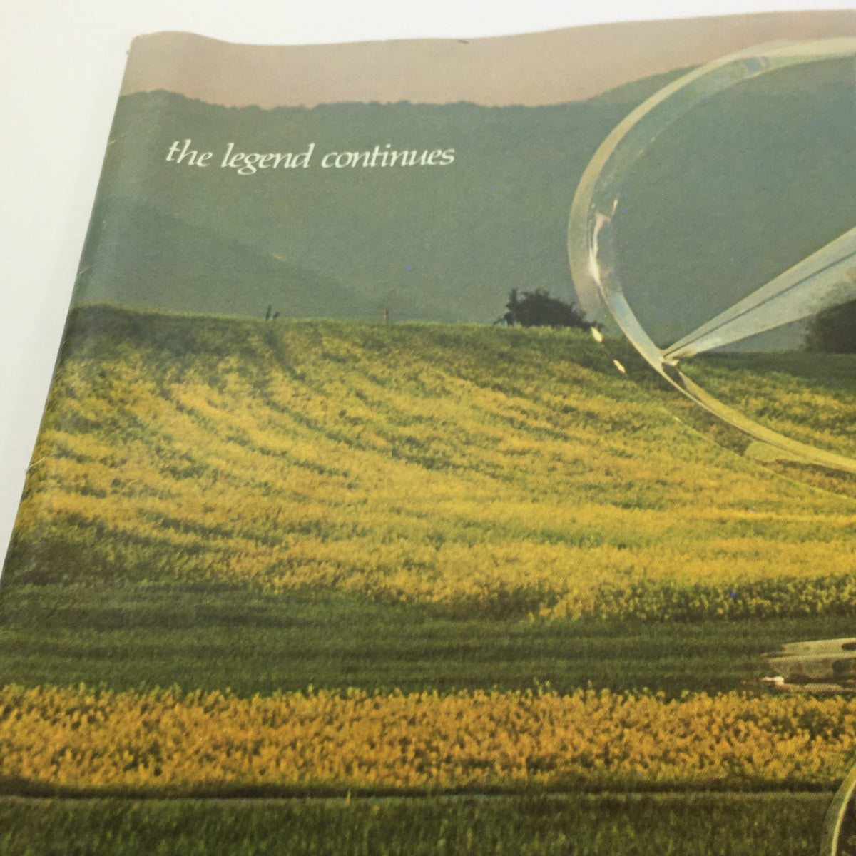 Cover of the 1970s Mercedes-Benz 280SE 450SEL 450SL Dealership Car Auto Brochure Catalog showcasing scenic fields with the text 'the legend continues'.