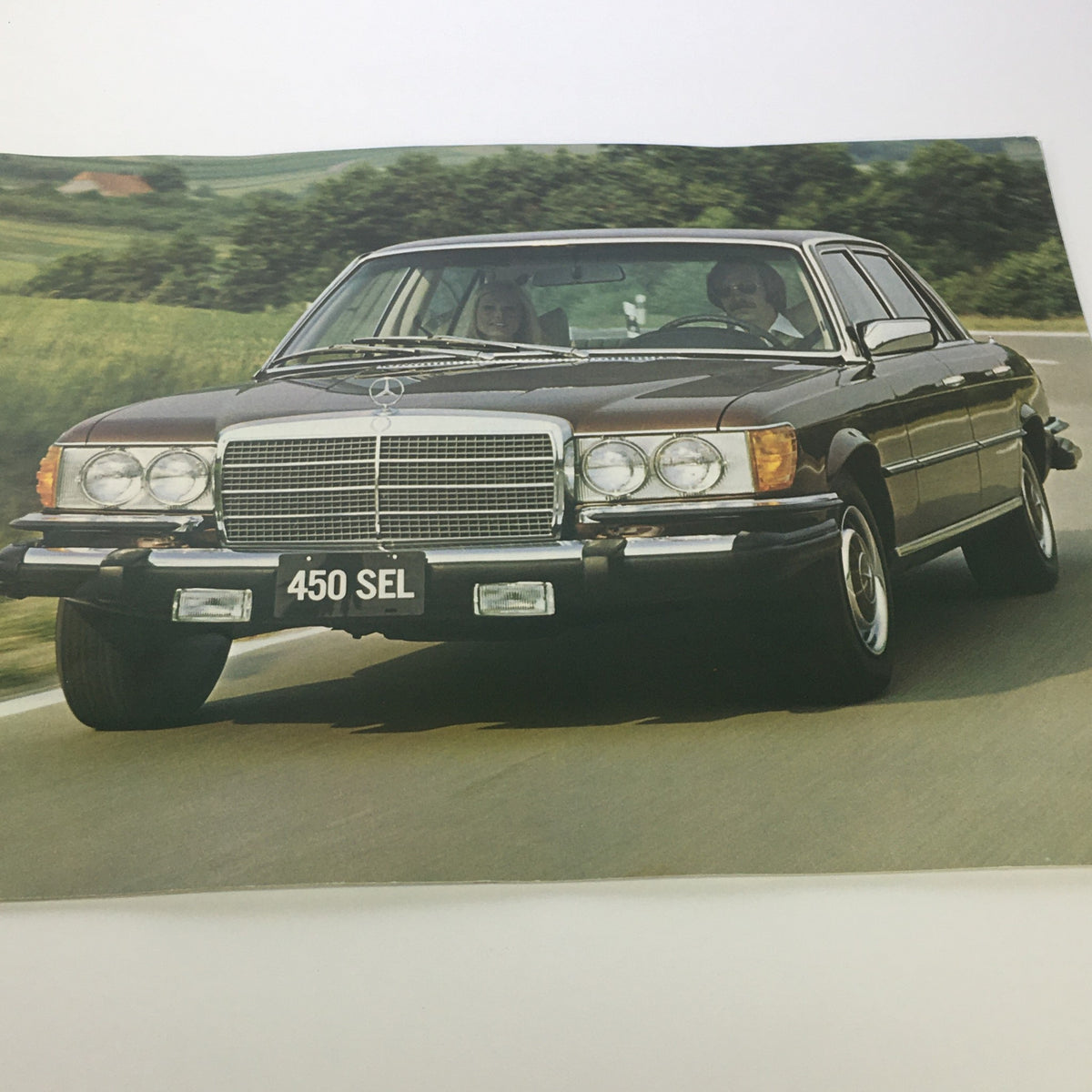 1970s Mercedes-Benz 450SEL showcased on the road with two passengers, featured in the Mercedes-Benz 280SE 450SEL 450SL Dealership Car Auto Brochure Catalog.
