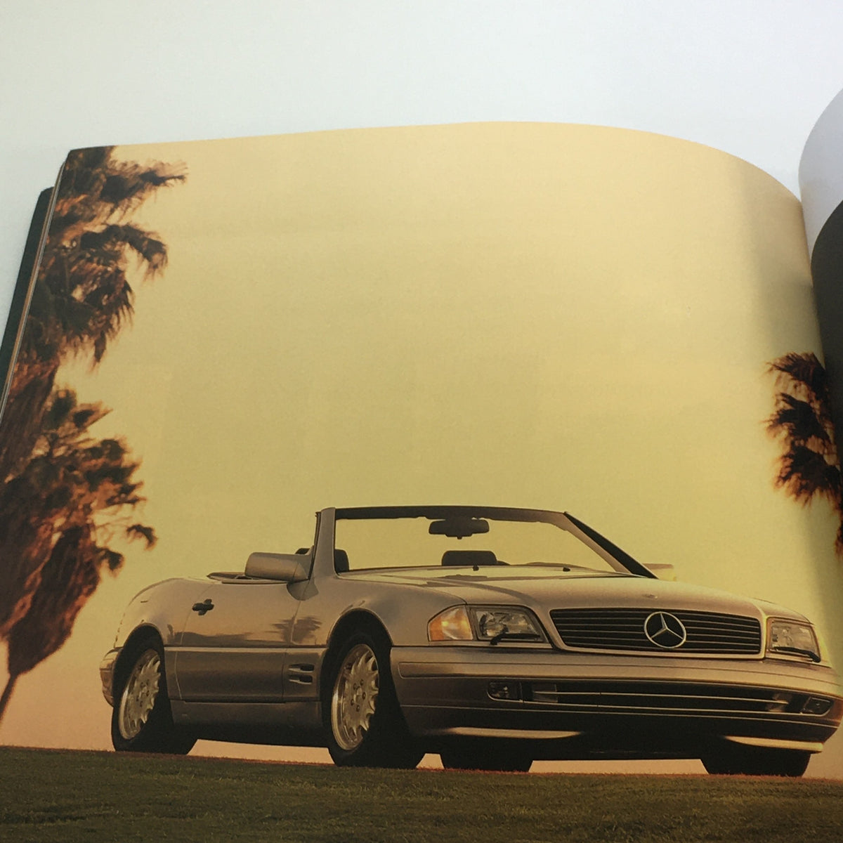 Colorful image from the 1996 Mercedes-Benz Dreams SL-Class Dealership Car Auto Brochure Catalog featuring a silver Mercedes SL-Class convertible in a scenic outdoor setting.