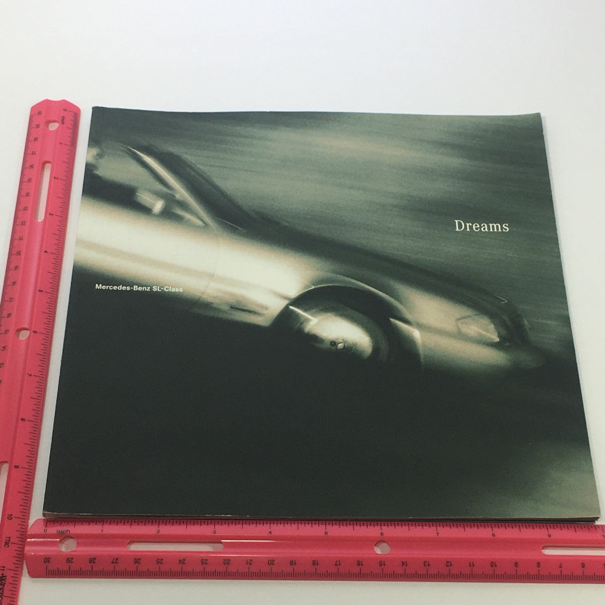 1996 Mercedes-Benz Dreams SL-Class Dealership Car Auto Brochure Catalog cover featuring a dynamic image of a silver Mercedes-Benz SL-Class on a blurred background, emphasizing the sleek design and luxury appeal of the vehicle.