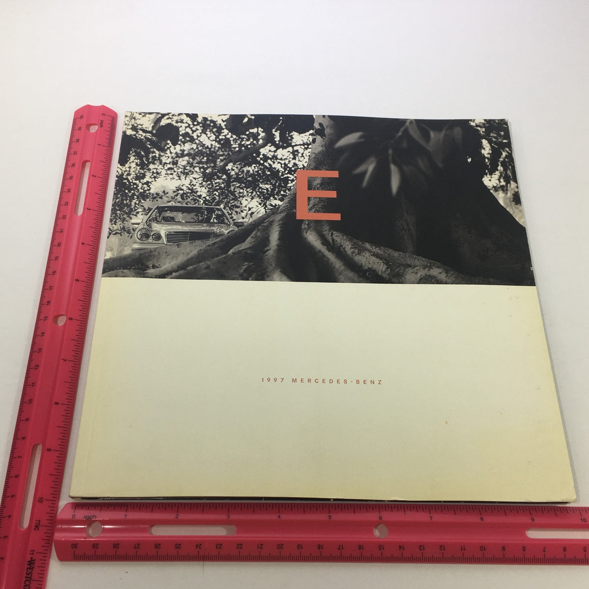 Cover of the 1997 Mercedes-Benz E-Class Dealership Car Auto Brochure Catalog showcasing a stylized 'E' design against a backdrop of a tree, indicating its vintage automotive theme.