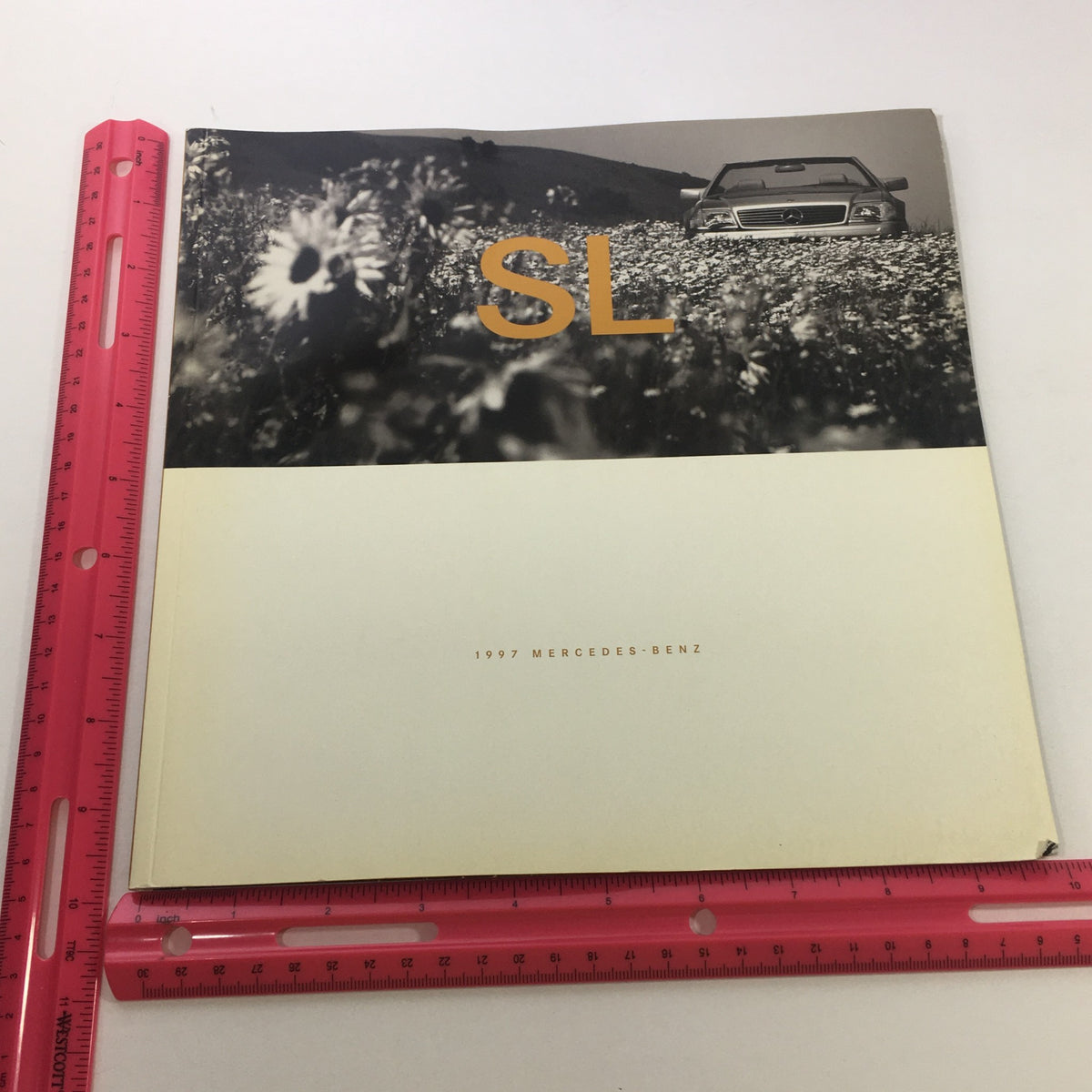 1997 Mercedes-Benz SL-Class Dealership Car Auto Brochure Catalog displaying the front cover with 'SL' title and a vintage photograph of the SL-Class model amidst flowers, symbolizing elegance and style.