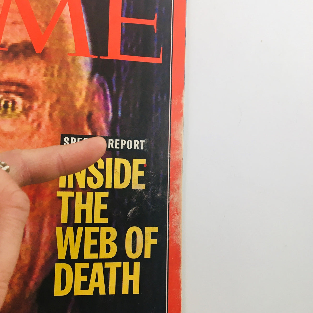 Close-up view of the Time Magazine cover dated April 7, 1997, highlighting the title 'Inside the Web of Death' with a finger pointing towards the text for emphasis.
