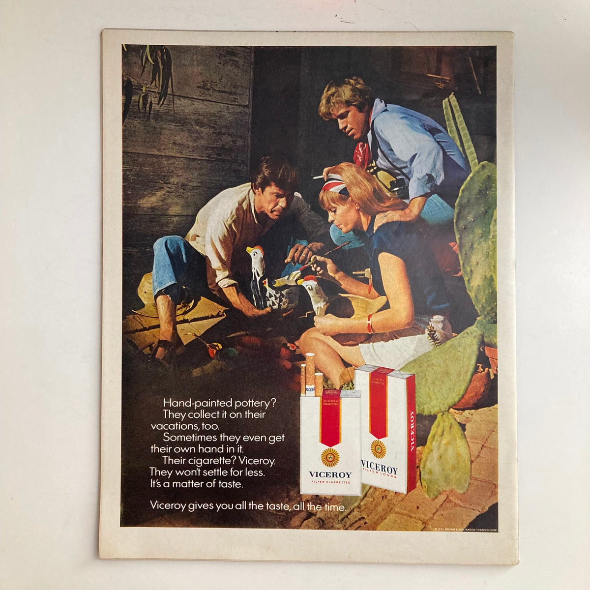 Vintage advertisement from a magazine showcasing three people engaged in a creative activity with hand-painted pottery, alongside a Viceroy cigarette advertisement, highlighting the nostalgic aesthetic of the early 1970s.
