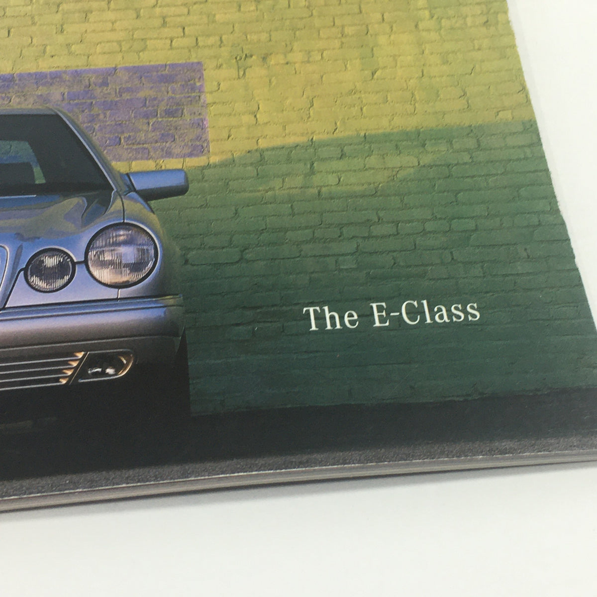 Close-up of the 1999 Mercedes-Benz E-Class Dealership Car Auto Brochure Catalog showcasing the silver Mercedes-Benz E-Class vehicle and the text 'The E-Class'.
