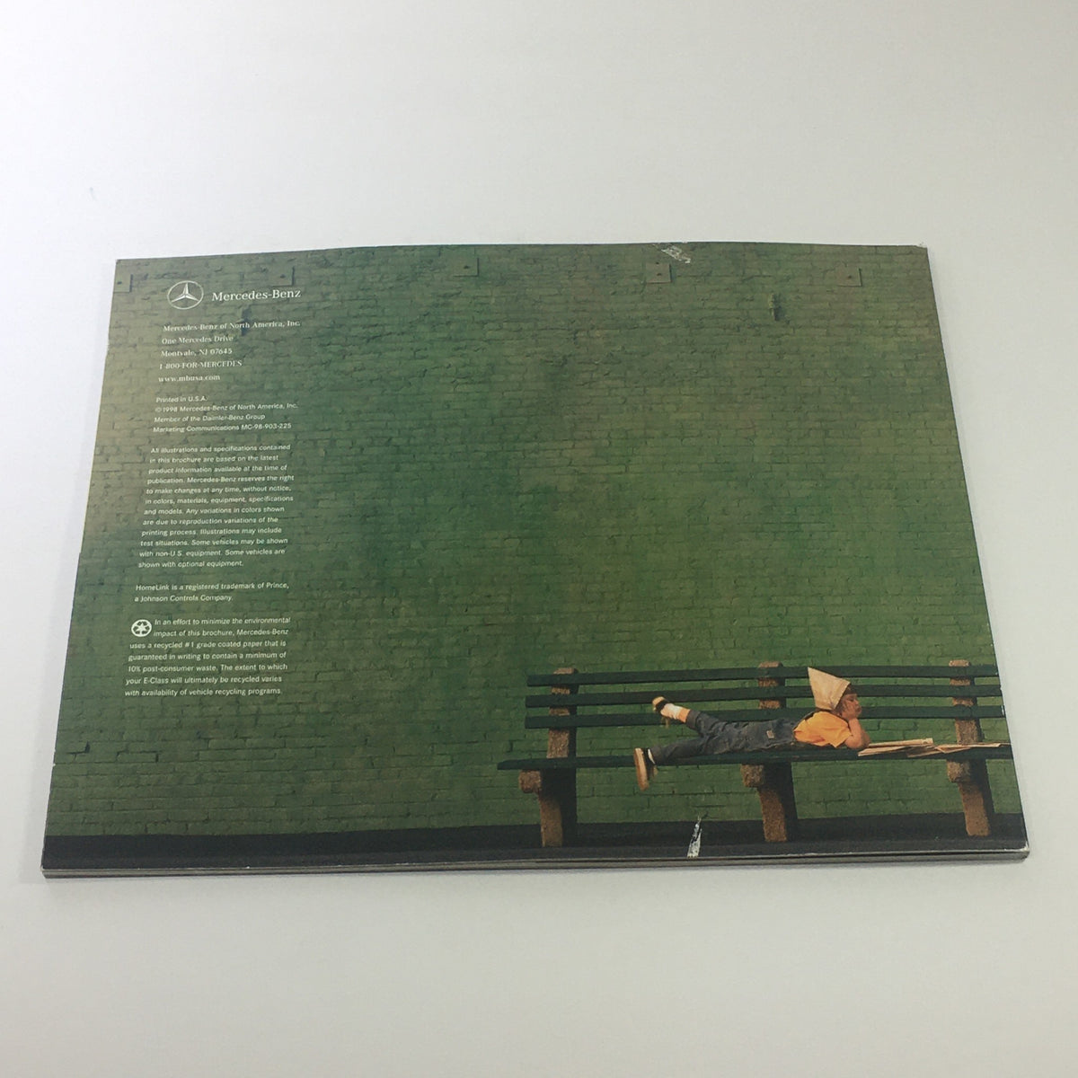 Back cover of the 1999 Mercedes-Benz E-Class Dealership Car Auto Brochure Catalog with a child resting on a bench against a green wall.