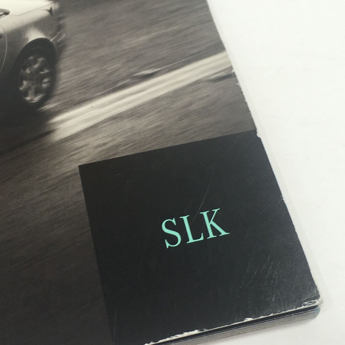 Close-up of the 'SLK' title on the cover of the 2000 Mercedes-Benz Designo Editions Dealership Car Auto Brochure Catalog.