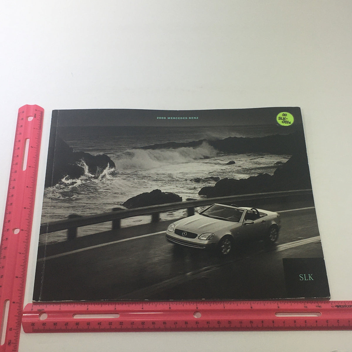 Front cover of the 2000 Mercedes-Benz SLK Designo Editions dealership car auto brochure catalog, showcasing a sleek SLK model driving along a coastal road with a scenic backdrop.