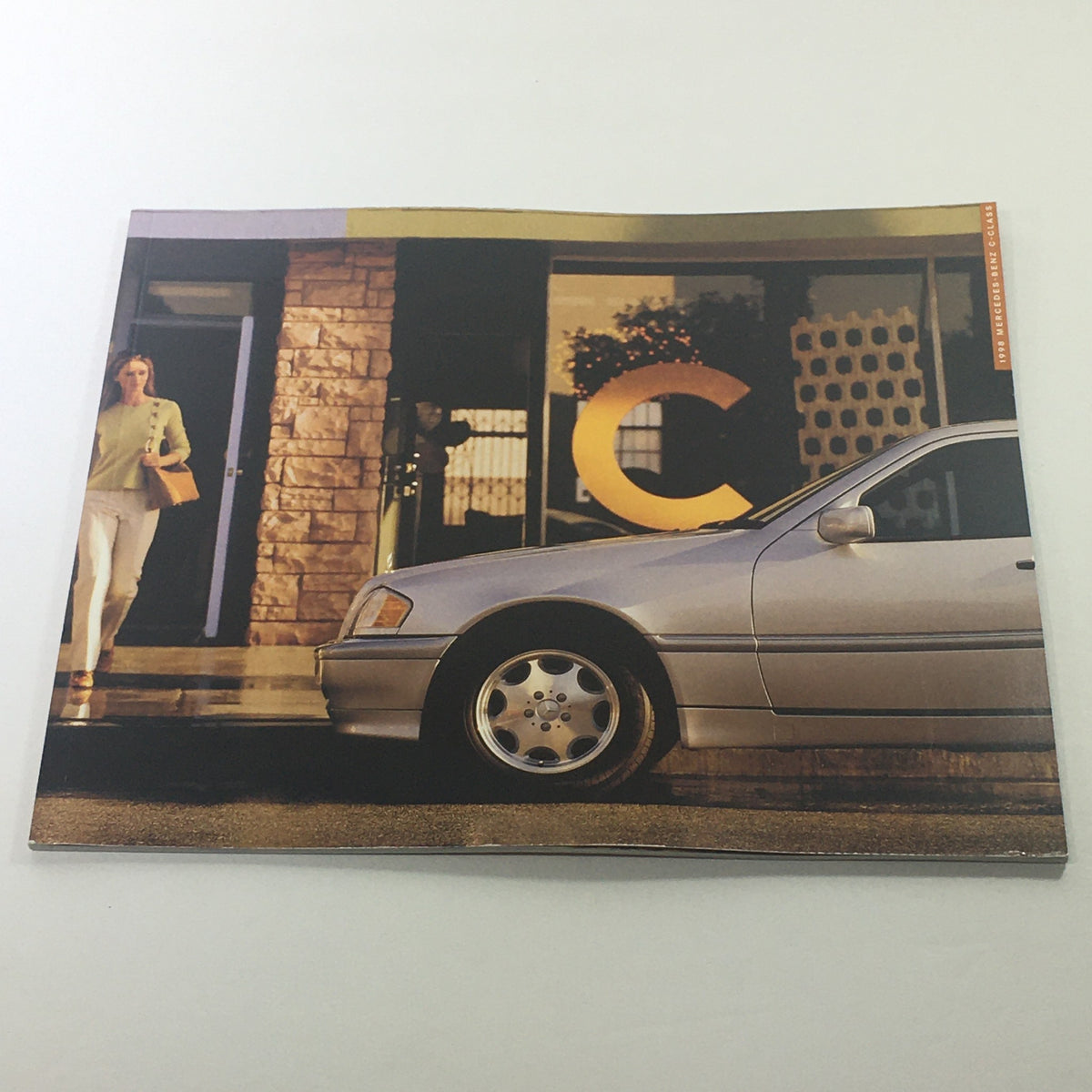 1998 Mercedes-Benz C-Class Dealership Car Auto Brochure Catalog showcasing a silver car beside a dealership, highlighting the stylish design and professional setting.