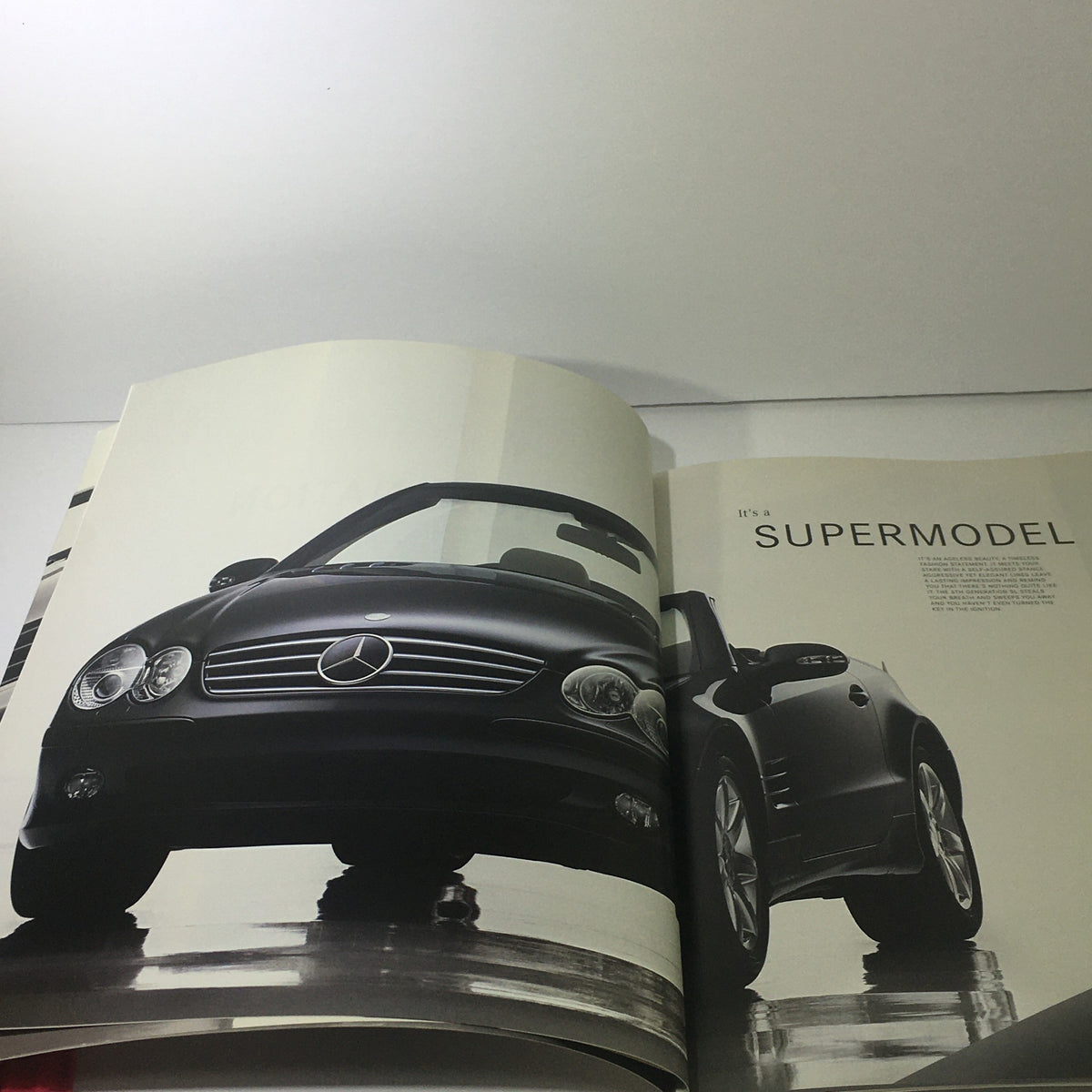 Inside spread of the 2003 Mercedes-Benz 5th Generation SL-Class Dealership Car Auto Brochure Catalog featuring a stylish SL-Class with the heading 'IT'S A SUPERMODEL'.