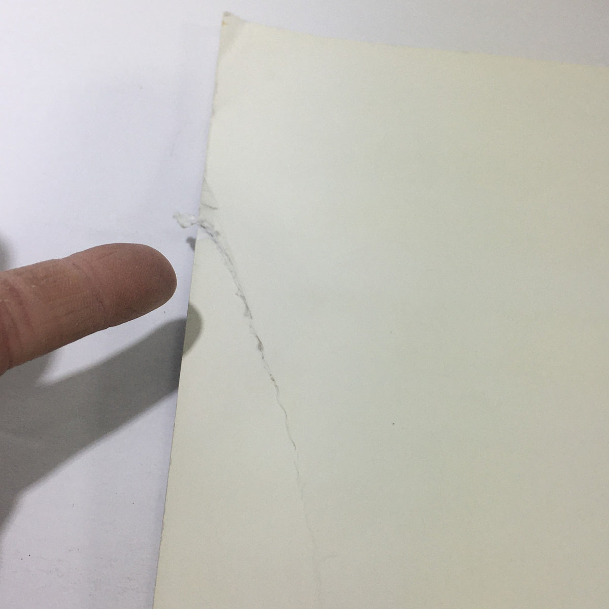 Close-up of a minor rip on the back cover of the 2003 Mercedes-Benz 5th Generation SL-Class Dealership Car Auto Brochure Catalog, illustrating its used condition.