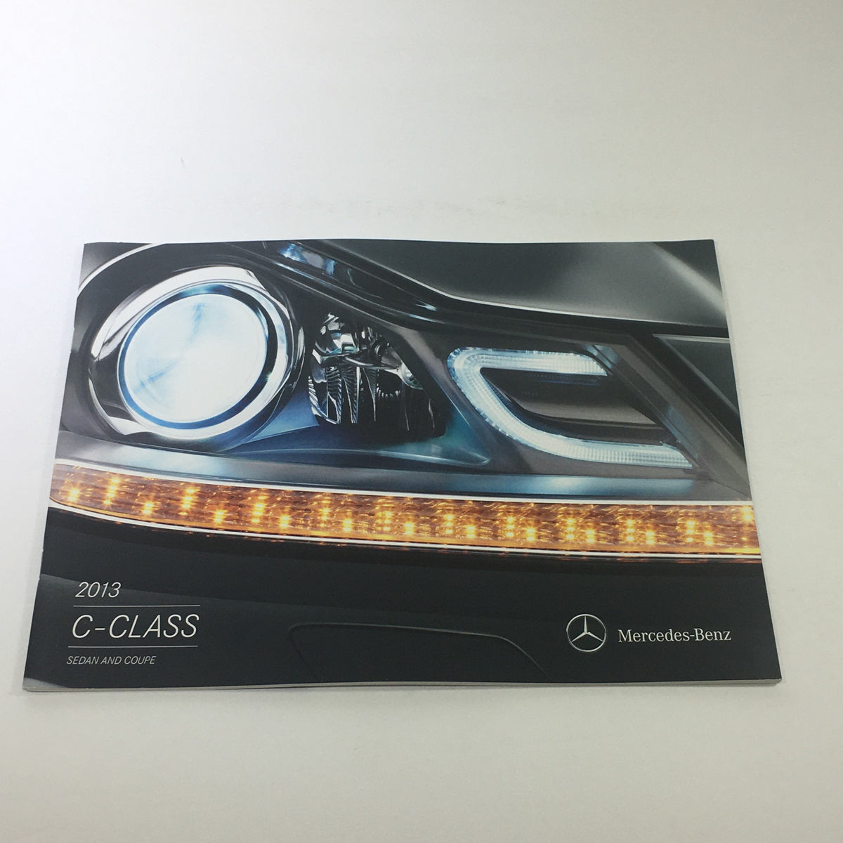 2013 Mercedes-Benz C-Class Sedan and Coupe Dealership Car Auto Brochure Catalog cover image featuring the sleek headlight design of the car.