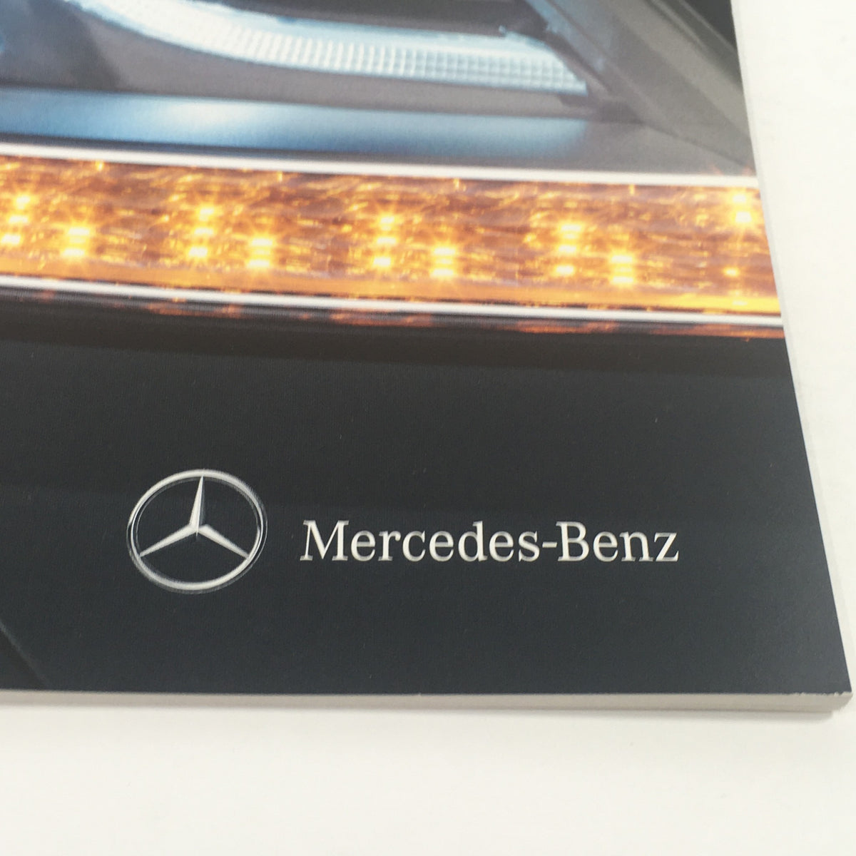 Close-up of the Mercedes-Benz logo on the cover of the 2013 Mercedes-Benz C-Class Sedan and Coupe Dealership Car Auto Brochure Catalog.