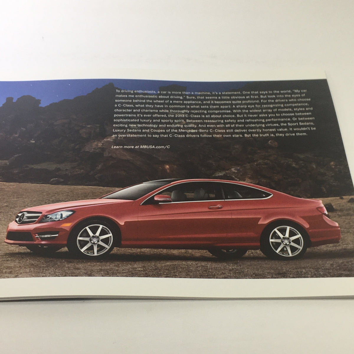 Image of a red 2013 Mercedes-Benz C-Class Coupe showcased in a scenic outdoor location from the dealership brochure.