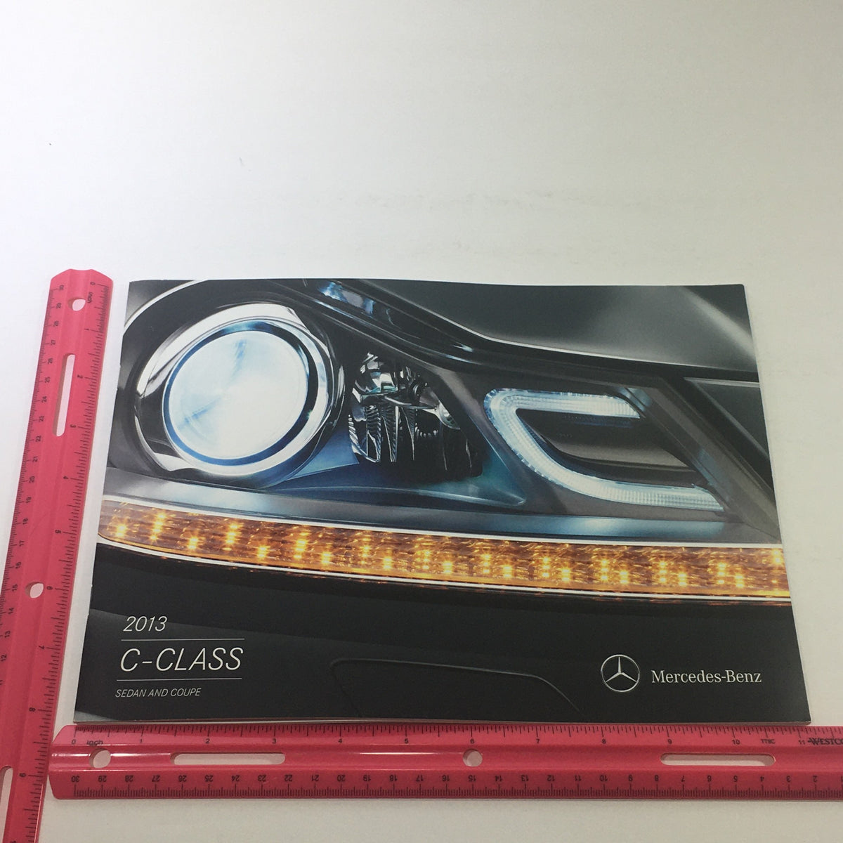 Cover of the 2013 Mercedes-Benz C-Class Sedan and Coupe Dealership Car Auto Brochure Catalog, featuring a close-up of the vehicle's headlight and stylish front design.