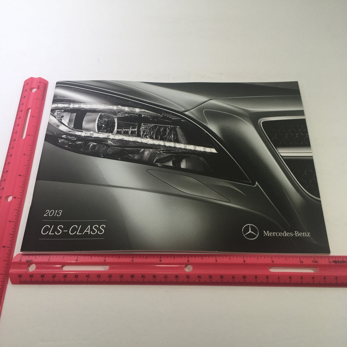 Front cover of the 2013 Mercedes-Benz CLS-Class Dealership Car Auto Brochure Catalog illustrating a close-up of the sleek headlamp and stylish design.