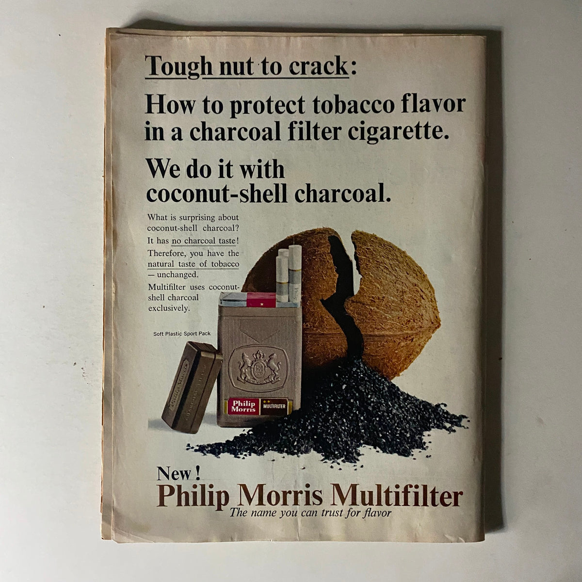 Advertisement from a vintage magazine showing Philip Morris Multifilter cigarettes, promoting protection of tobacco flavor using coconut-shell charcoal. Historical context from the 1960s era.