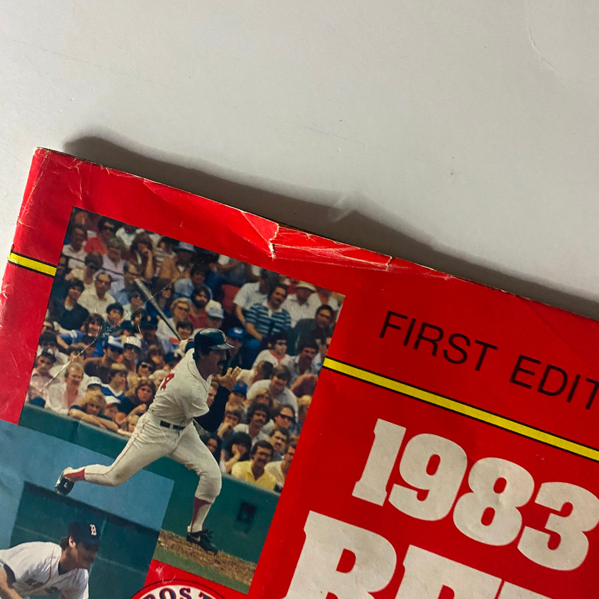 Close-up of the cover of the 1983 Boston Red Sox Official Scorebook Magazine First Edition, highlighting vintage baseball graphics and details.