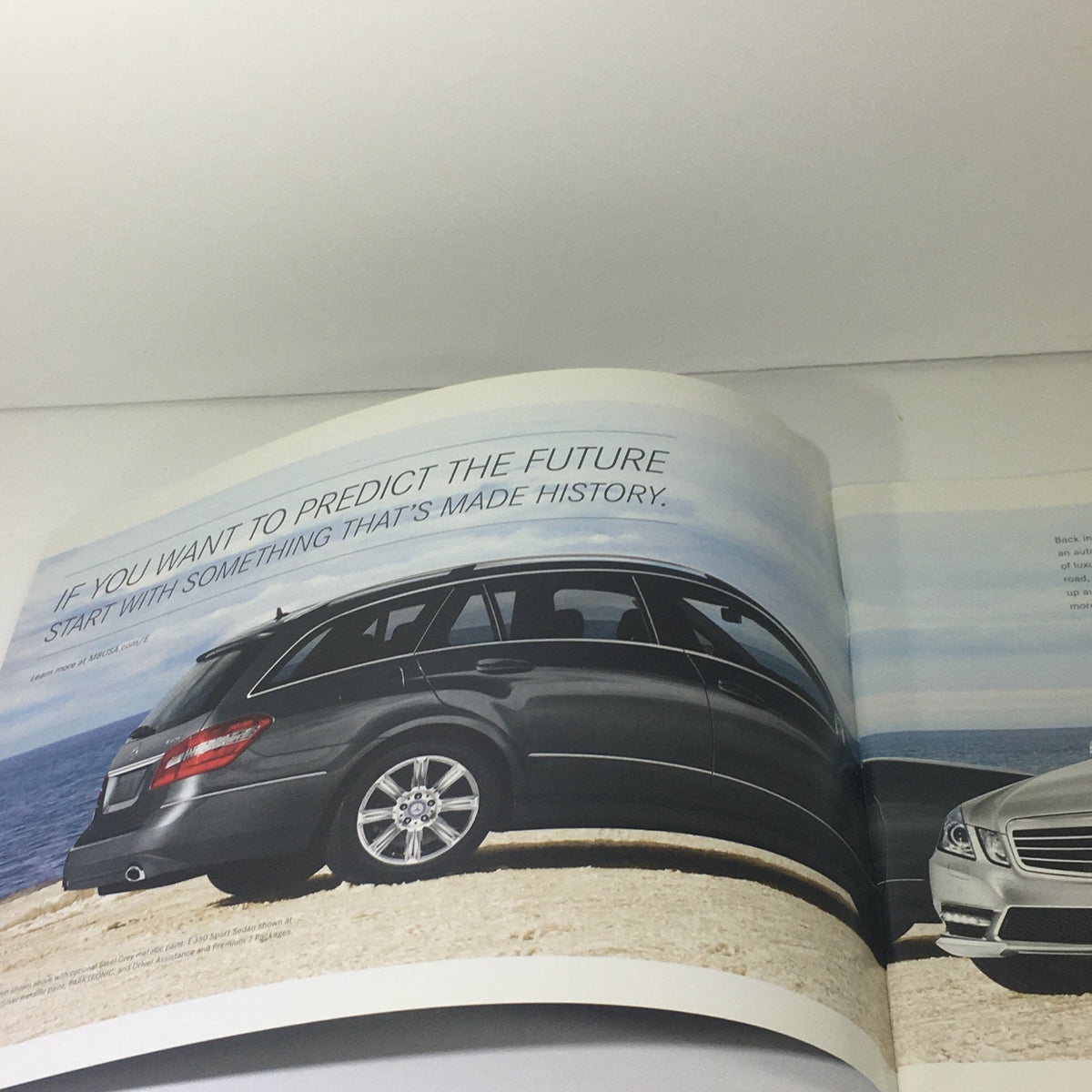 Interior page of the 2013 Mercedes-Benz E-Class Sedan and Wagon Dealership Car Auto Brochure featuring a black E-Class model with a scenic seaside background.