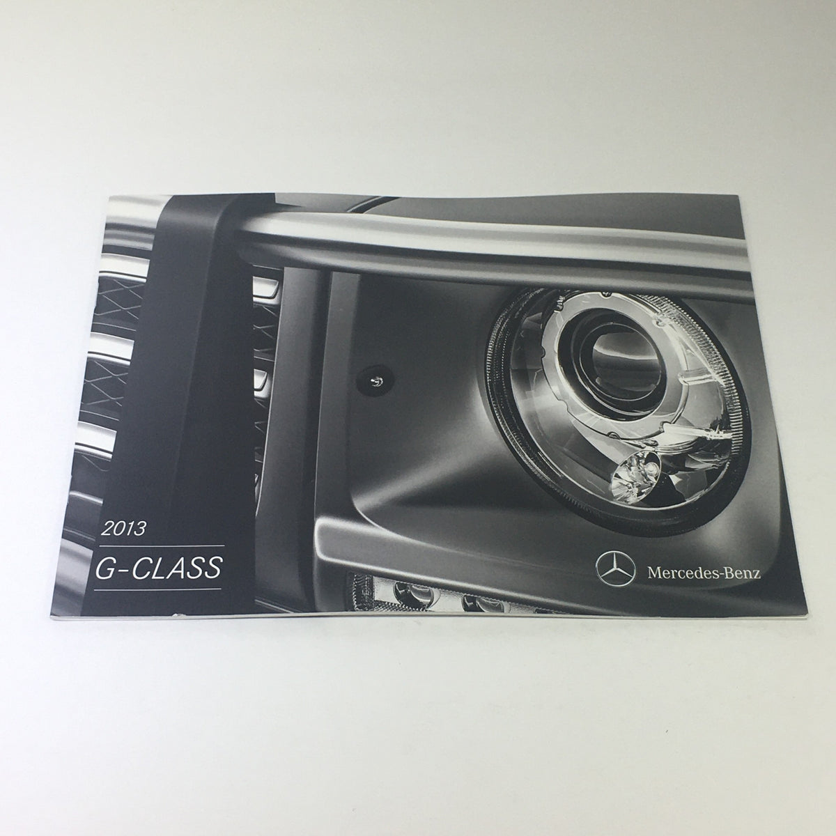 2013 Mercedes-Benz G-Class 4x4 AMG dealership car auto brochure catalog featuring a close-up of the vehicle's headlight design.