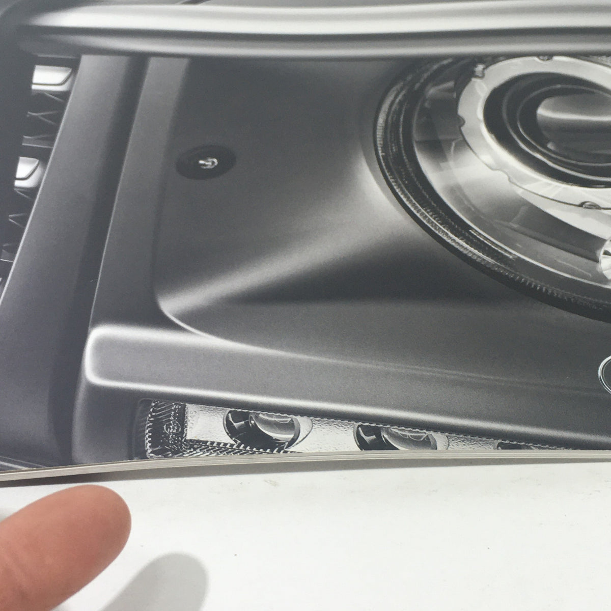 Close-up of 2013 Mercedes-Benz G-Class components in the dealership brochure, showcasing detailed craftsmanship and modern features.