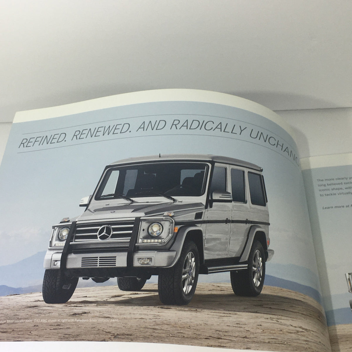 Promotional image from the 2013 Mercedes-Benz G-Class 4x4 AMG brochure highlighting the refined exterior of the model against a mountainous landscape.