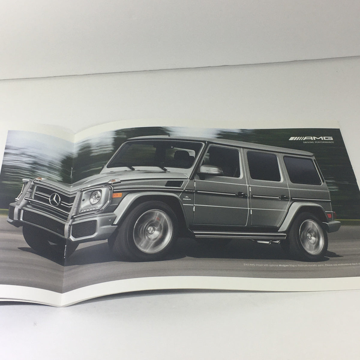 Dynamic imagery of the 2013 Mercedes-Benz G-Class 4x4 AMG in motion from the dealership brochure, illustrating the vehicle's performance and athletic design.