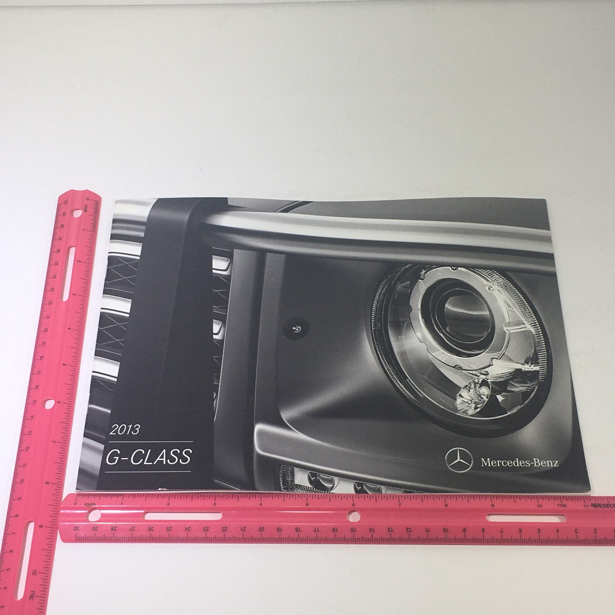 Front cover of the 2013 Mercedes-Benz G-Class 4x4 AMG Dealership Car Auto Brochure Catalog showcasing a detailed image of the vehicle.