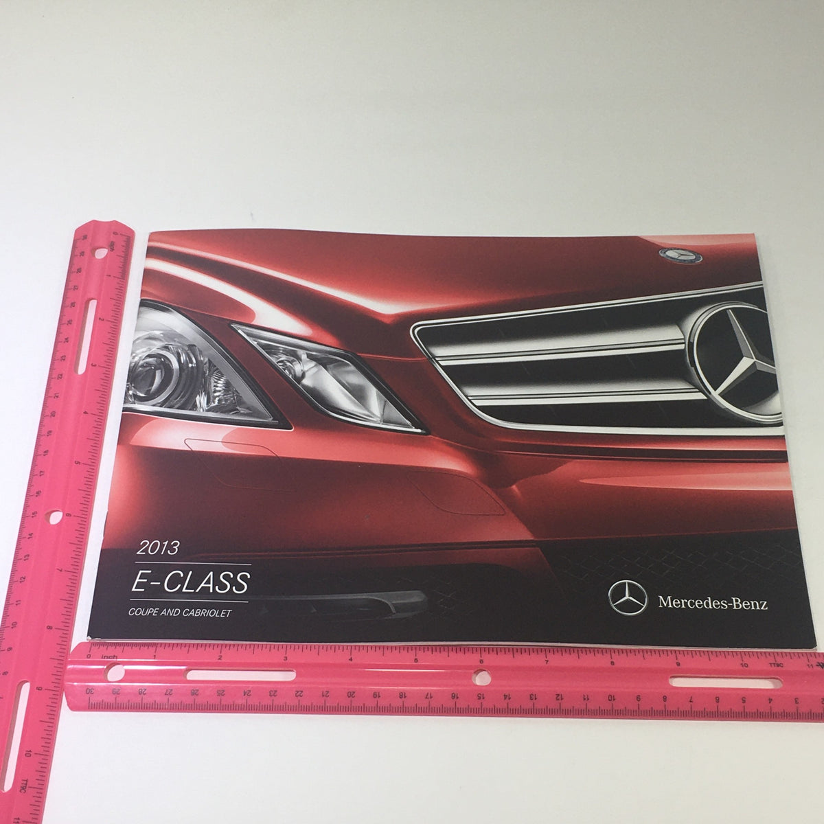 2013 Mercedes-Benz E-Class Coupe Cabriolet Auto Brochure featuring a sleek design and close-up of the vehicle's front grille and headlights, showcasing its luxury appeal and detailed specifications.