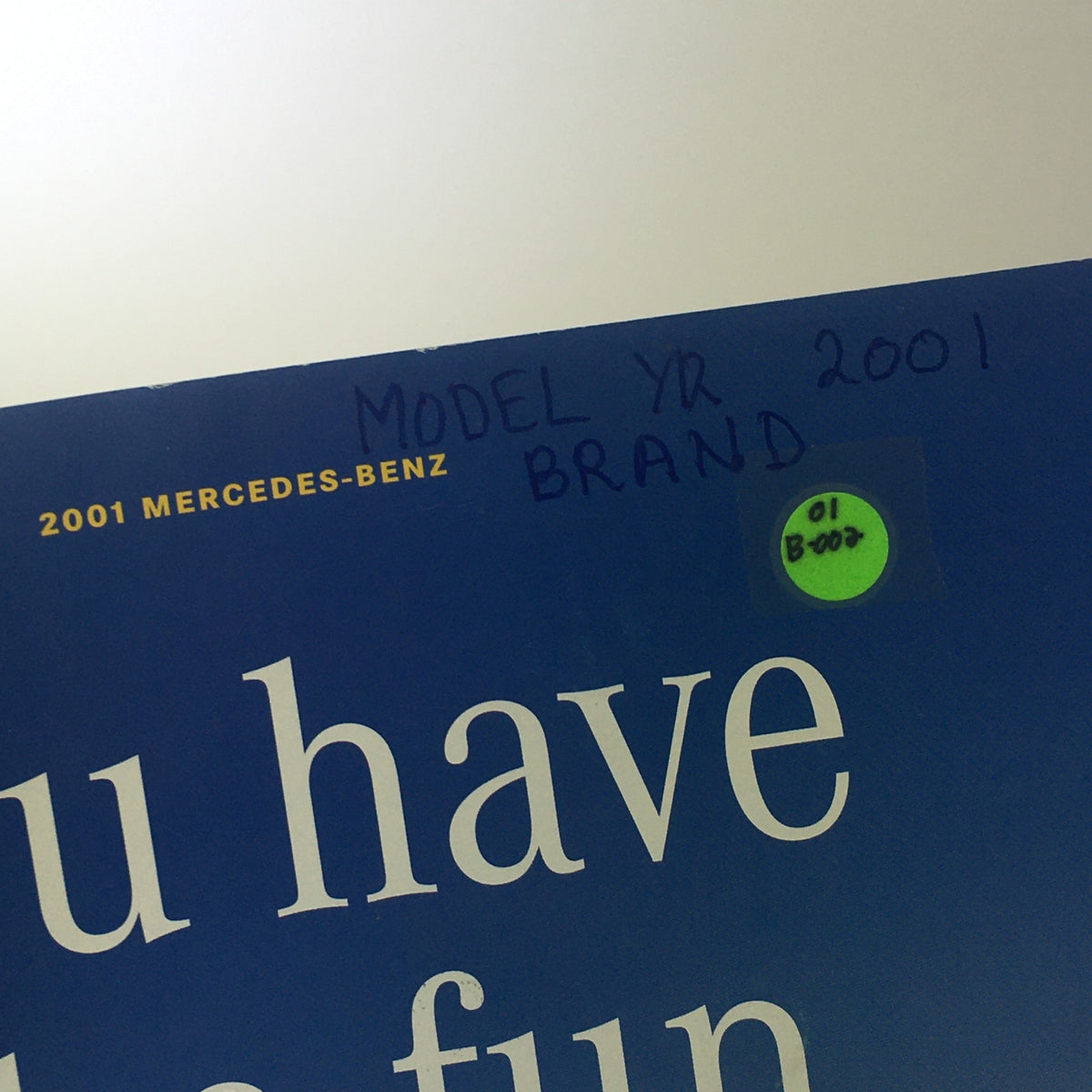 Close-up image of the corner of the 2001 Mercedes-Benz SLK-Class Dealership Car Auto Brochure Catalog showing a handwritten note indicating 'MODEL YR 2001' and a green sticker with '01 Boo'.