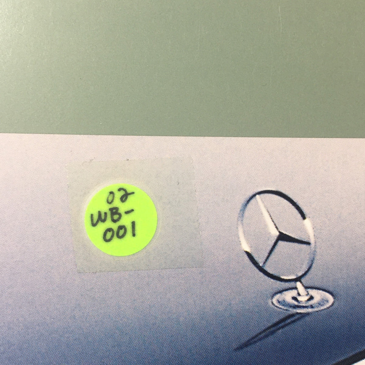 Close-up of a sticker on the 2001 Mercedes-Benz E-Class Dealership Car Auto Brochure Catalog, indicating ID number WB-001.