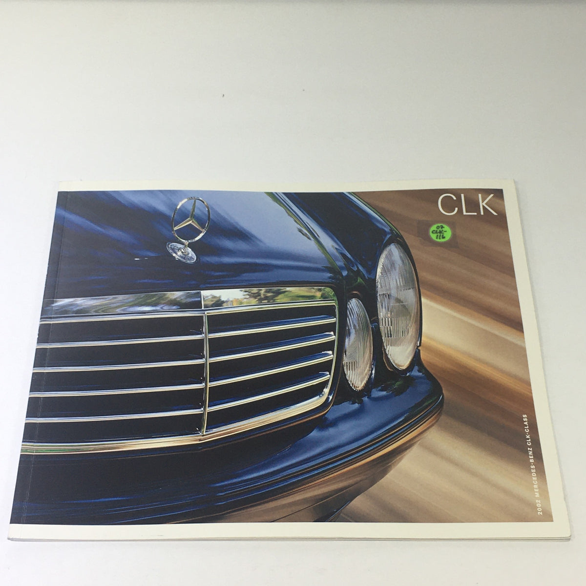 2002 Mercedes-Benz CLK-Class Dealership Car Auto Brochure Catalog featuring the front grille and headlights of the car against a blurred background.