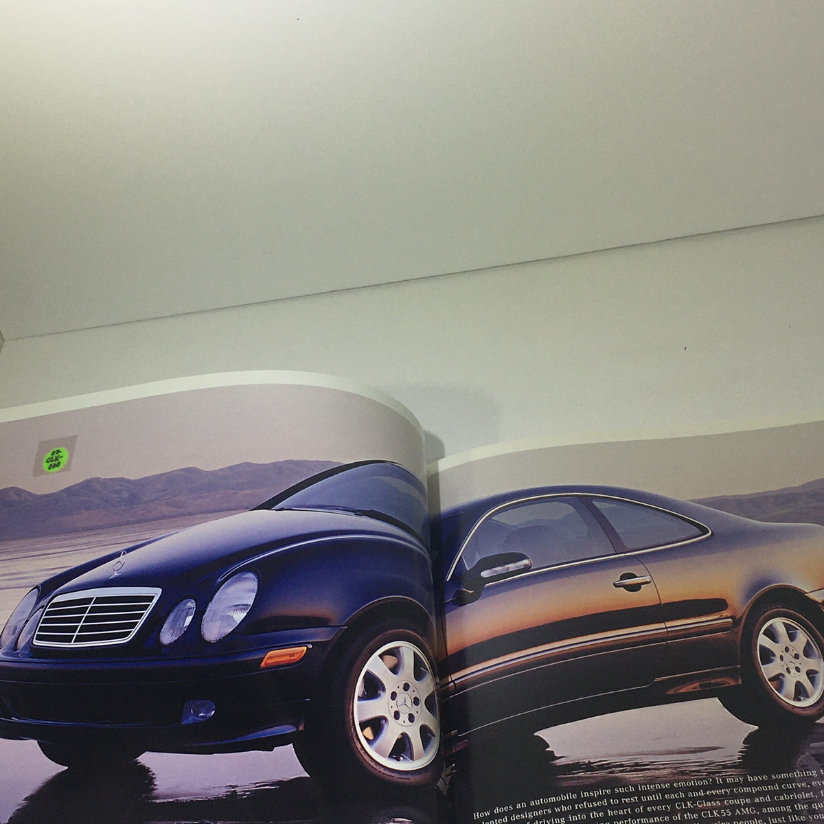 Interior page of the 2002 Mercedes-Benz CLK-Class Dealership Car Auto Brochure displaying a black Mercedes-Benz CLK-Class coupe parked in a scenic view.