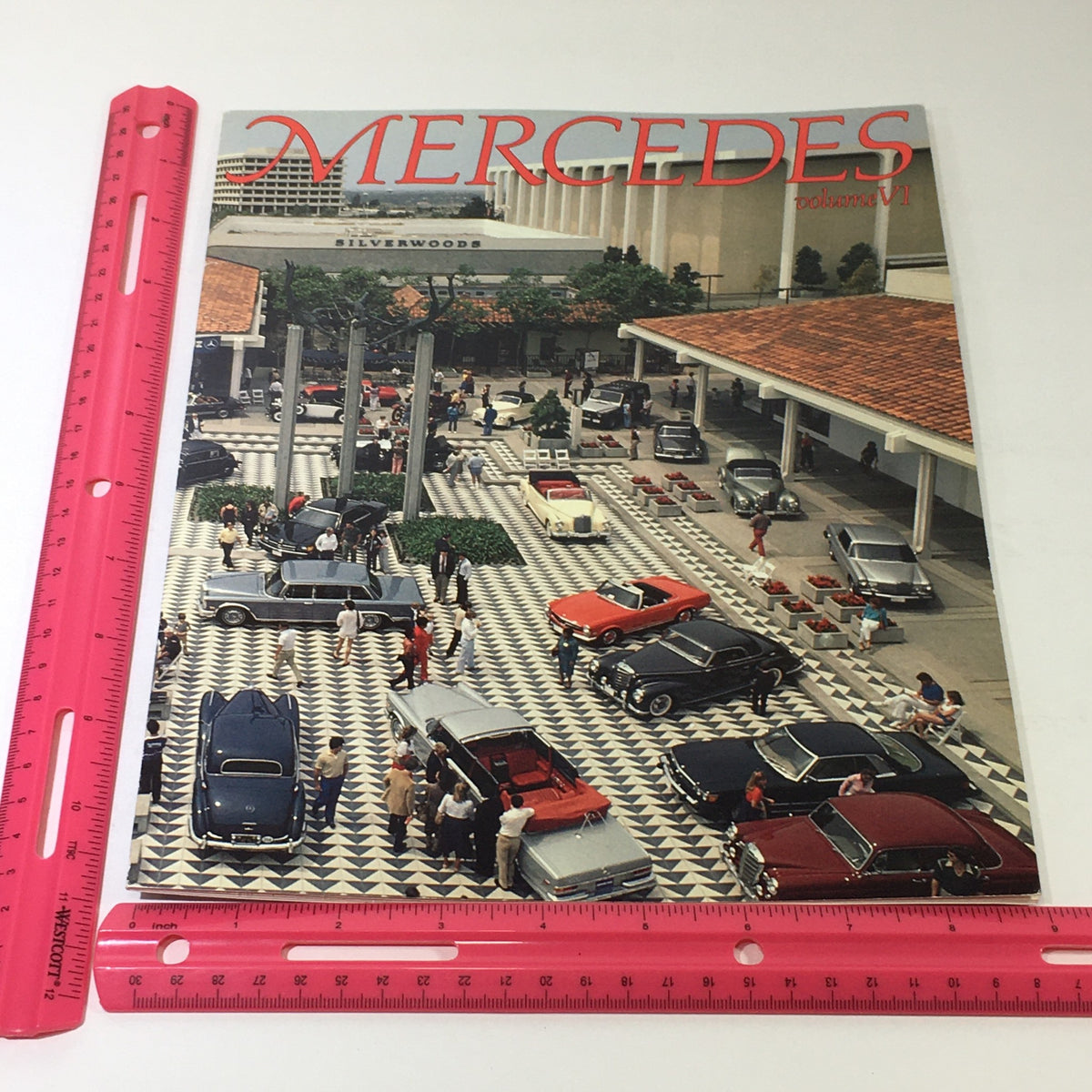 Cover image of the 1982 Mercedes-Benz Volume VI Dealership Car Auto Brochure Catalog, depicting a busy dealership lot with various classic Mercedes-Benz models and a stylish entrance.