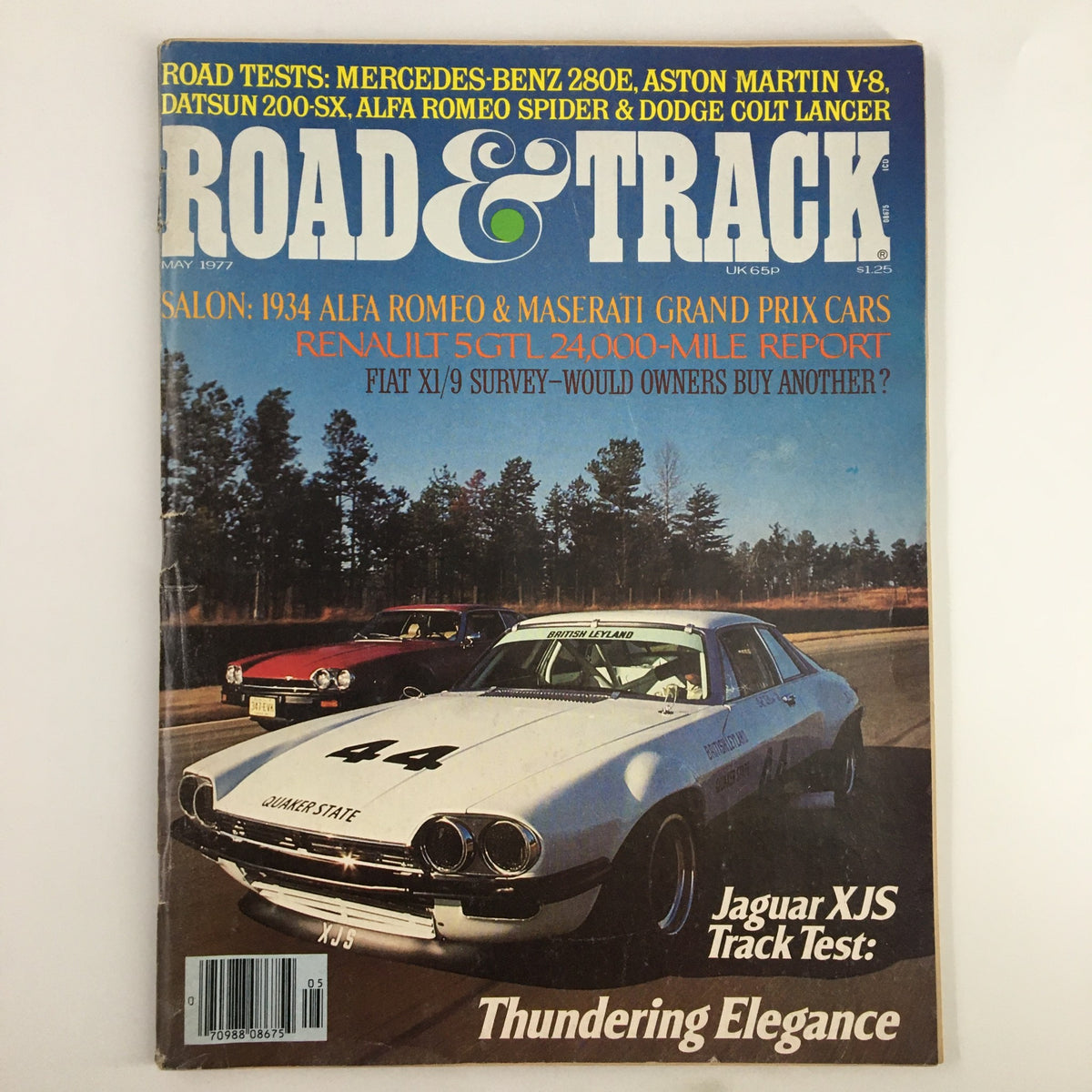 Cover of VTG Road & Track Magazine May 1977 featuring the Jaguar XJS Track Test, showcasing a white Jaguar XJS race car with the number 44 on a race track, emphasizing its elegance in automotive design.