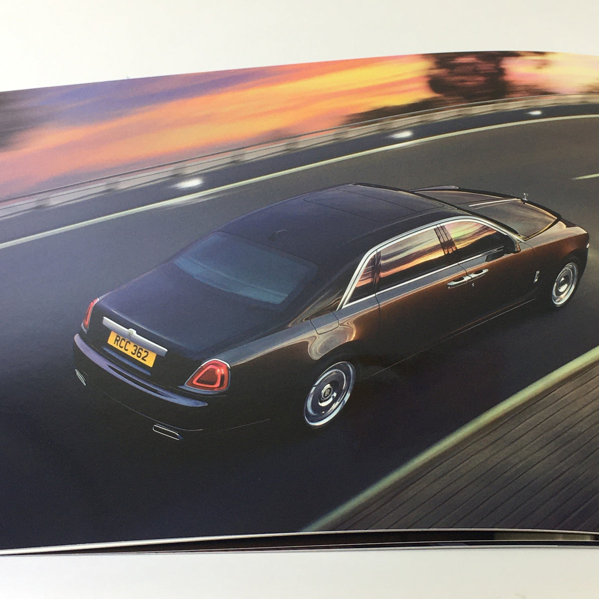 Aerial view of the 2014 Rolls Royce Ghost captured in motion, featured in the Ghost Family Dealership Car Auto Brochure Catalog, illustrating its sleek design.