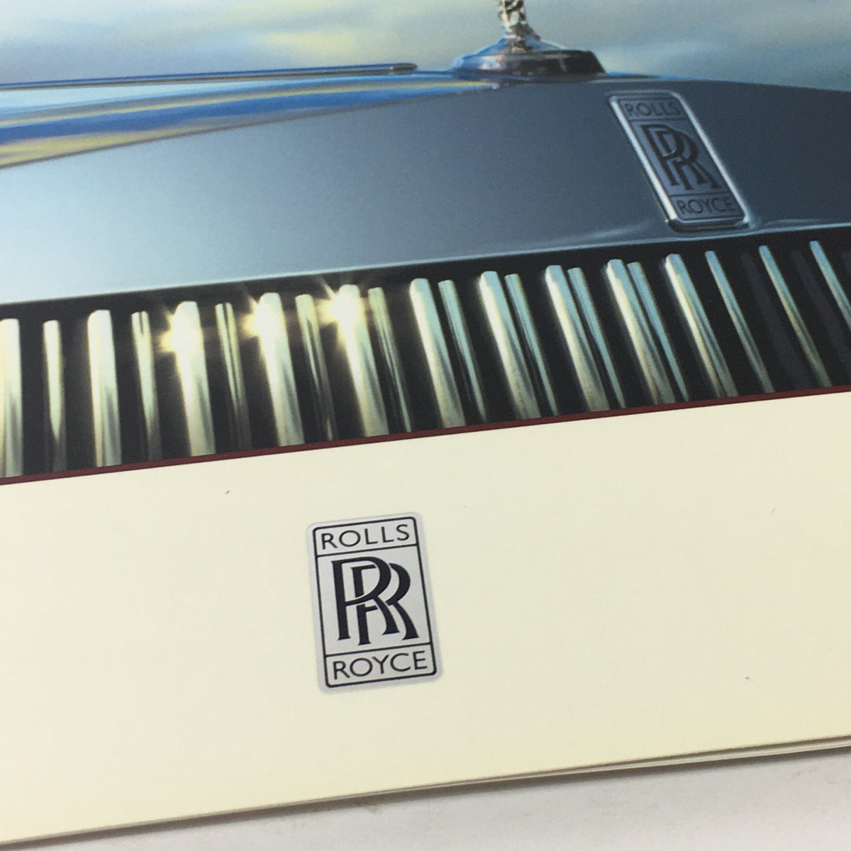 Close-up of the Rolls Royce emblem on the 2013 Rolls Royce Provenance Collection Dealership Car Auto Brochure Catalog, highlighting the craftsmanship and branding of the luxury car manufacturer.