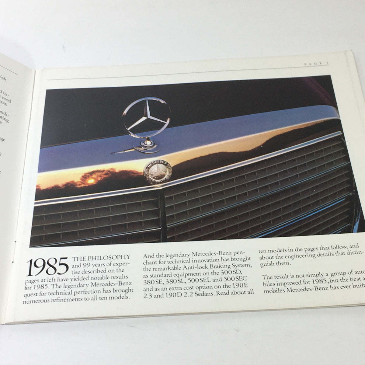 Detailed photo of the Mercedes-Benz emblem on a vehicle from the 1985 SD SE SL SEL SEC Class in the brochure.