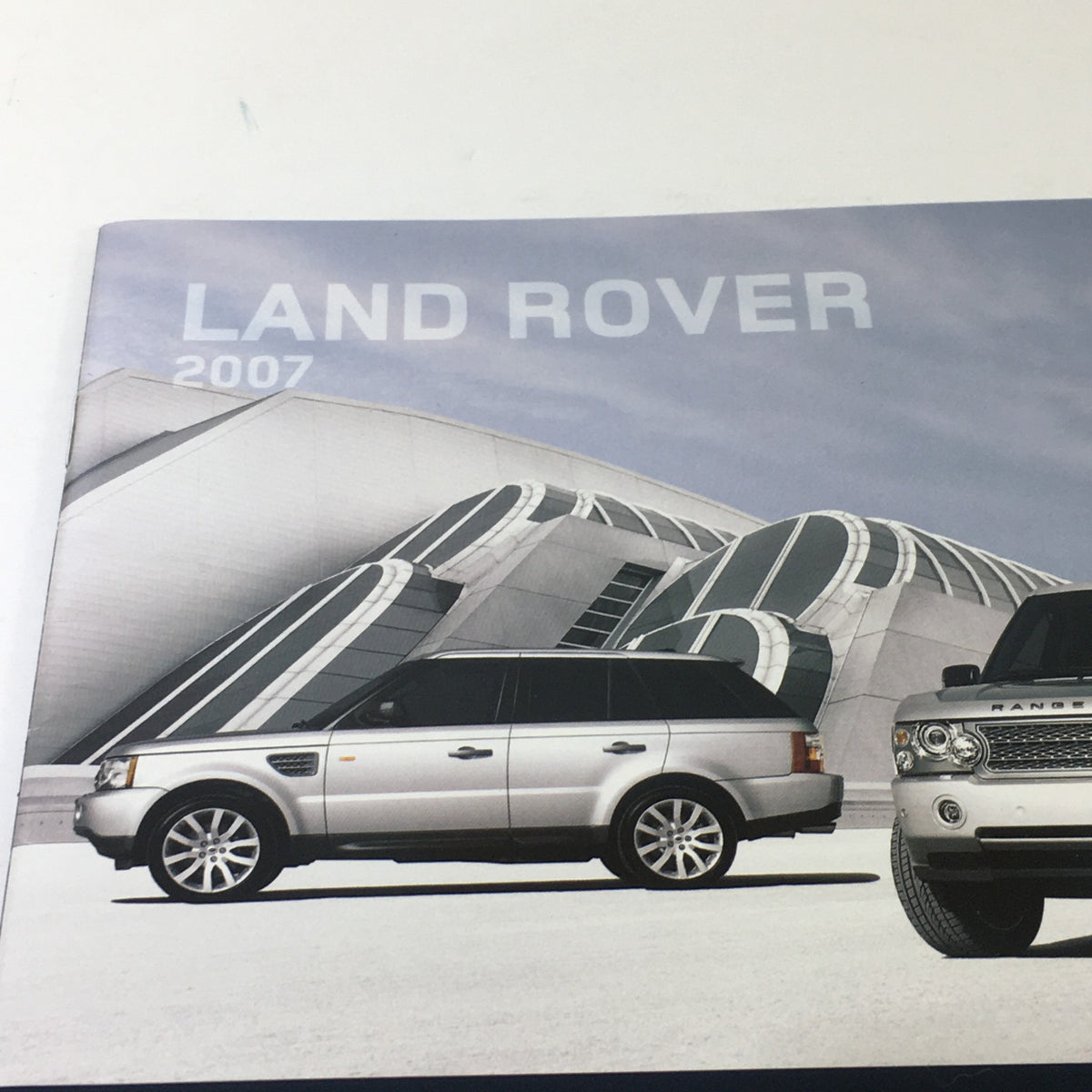 Close-up of the 2007 Land Rover American Cherry Dealership Car Auto Brochure Catalog cover highlighting a sleek silver SUV and contemporary architecture.